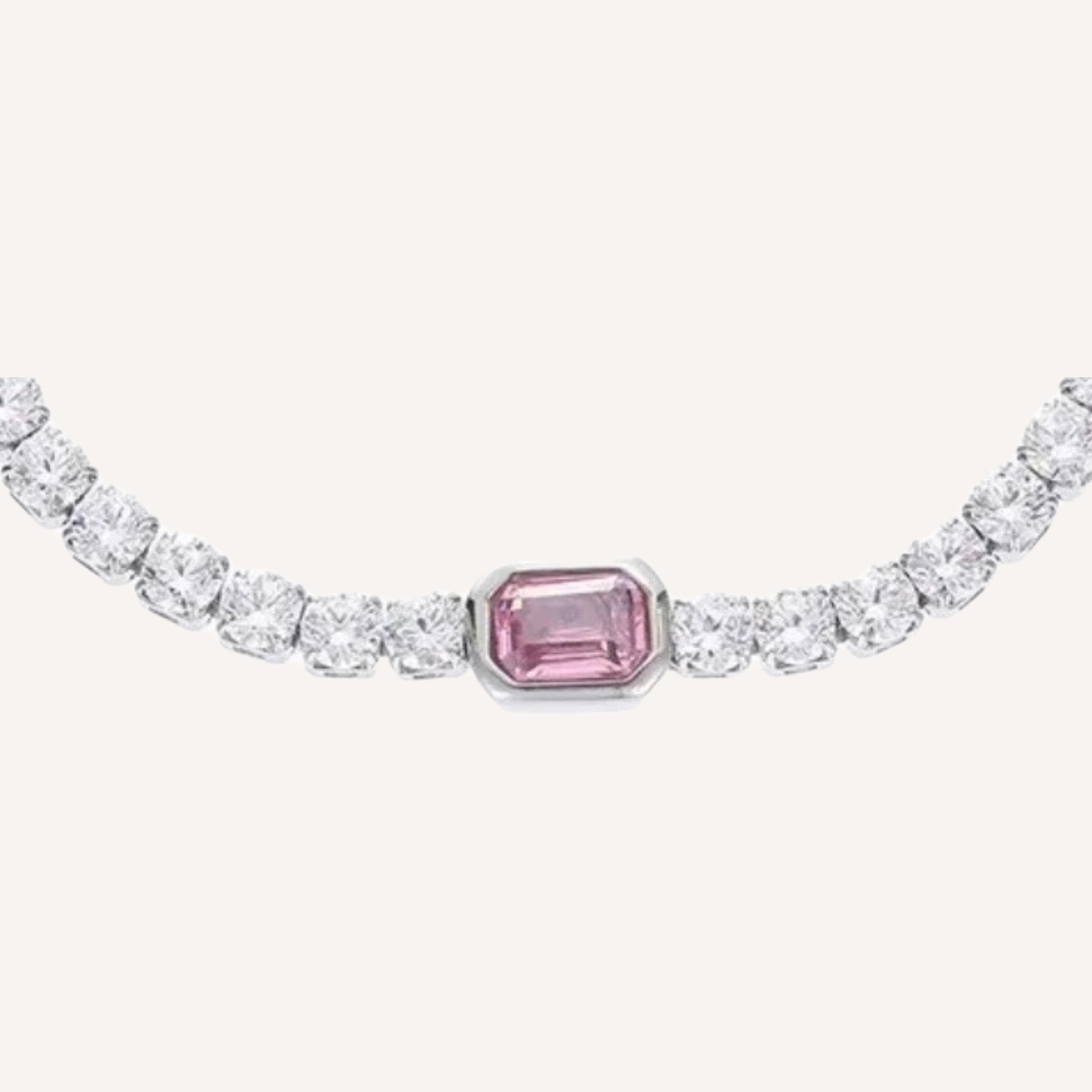 Ein Silber Tennisarmband mit runden Zirkonia steinen. Dr Hauptstein ist Rechteckig und ein rosa Zirkonia. Das Armband hat eine Verlängerungskette zur Verstellung der Größe, daran hängt ein Ovaler Anhänger der mit S.Steel eingraviert ist.